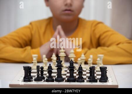 Sitzt an einem Tisch und spielt Schach. Das Kind konzentrierte sich auf das Spiel Stockfoto