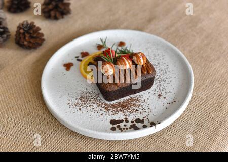 Top-Ansicht Schokolade Brownies mit auf Macadamia und Karamell in der weißen Schüssel auf Sacktuch Hintergrund. Hausgemachte Bäckerei oder Dessert Dekorieren mit Fres Stockfoto
