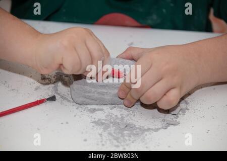 Bild eines Lernspiels, um Fossilien für einen kleinen Archäologen zu finden, mit Kindern Hände graben Stockfoto