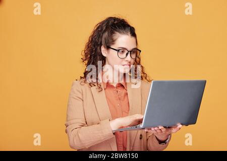 Seriöse junge Lehrerin oder Student in Brillen und formalwear Blick auf Laptop-Display während der Vorbereitung Präsentation für das Seminar Stockfoto