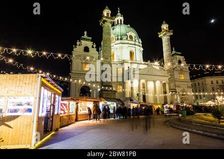 WIEN, ÖSTERREICH - 6. DEZEMBER 2016: Karlskirche und der Kunst-Advent-Weihnachtsmarkt in Wien bei Nacht. Die Unschärfe der Menschen ist zu sehen. Stockfoto