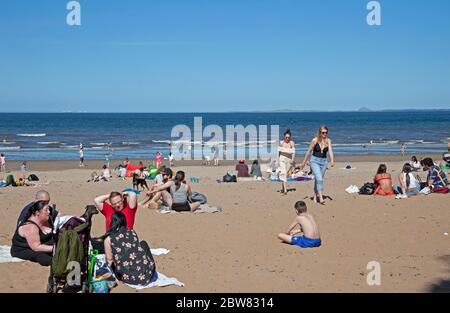 Portobello, Edinburgh, Schottland, Großbritannien. 30 Mai 2020. 24 Grad Celsius später Nachmittag mit einer steifen Brise, um die Temperatur erträglich zu halten, ein geschäftiger Strand und Promenade Menschen jung und alt enoying mehr Freiheit, andere zu treffen und haben sich niederzulassen Picknicks am ersten Wochenende nach voller Lockdown, aber vielleicht ein wenig locker mit der empfohlenen sozialen Distanz. Quelle: Arch White/Alamy Live News. Stockfoto