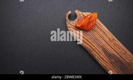 Natürliches Bernstein. Ein Stück gelb transparent Natur Bernstein auf einem Stück strukturiertes Holz, Hintergrund für Design Stockfoto