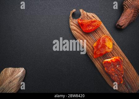 Natürliches Bernstein. Ein Stück gelb transparent Natur Bernstein auf einem Stück strukturiertes Holz, Hintergrund für Design Stockfoto