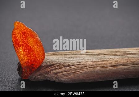 Natürliches Bernstein. Ein Stück gelb transparent Natur Bernstein auf einem Stück strukturiertes Holz, Hintergrund für Design Stockfoto