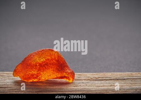 Natürliches Bernstein. Ein Stück gelb transparent Natur Bernstein auf einem Stück strukturiertes Holz, Hintergrund für Design Stockfoto