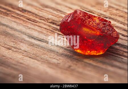 Natürliches Bernstein. Ein Stück gelb transparent Natur Bernstein auf einem Stück strukturiertes Holz, Hintergrund für Design Stockfoto