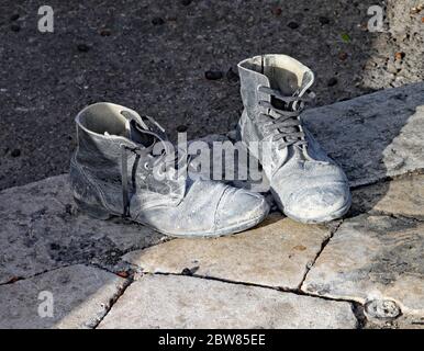 Ein Paar sehr alte und abgenutzte schwarze Stiefel auf dem Bürgersteig Stockfoto