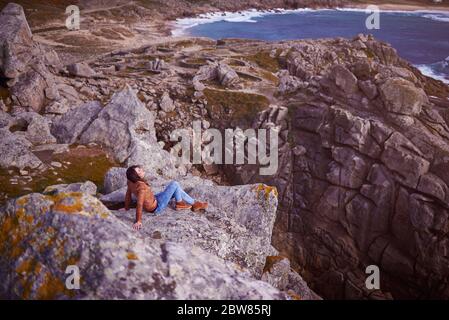 Junge Frau auf einem Felsen in der Nähe des Baroña celtic castro Stockfoto