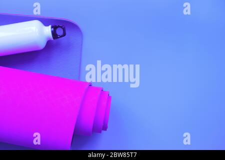 Leuchtend lila Yogamatte und eine Flasche Wasser. Stockfoto