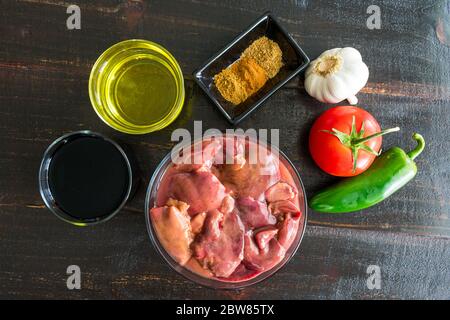 Gebratene Hühnerleber Zutaten: Rohe Hühnerlebern, Gewürze und andere Zutaten auf dunklem Holzhintergrund Stockfoto