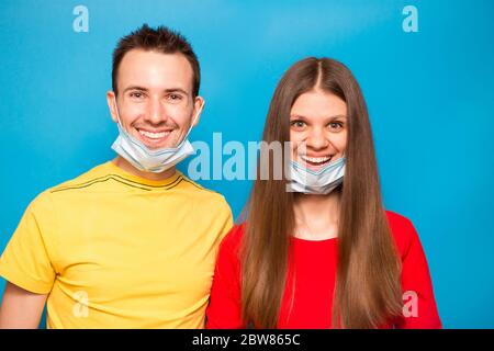 Happy Love Paar entfernen Schutzmaske isoliert auf blauem Hintergrund. Ende der Coronavirus-Pandemie, Quarantäne, Selbstisolierung. Die Krise von Covid-19 ist vorbei Stockfoto