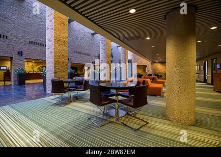 Innenansicht der Hotellobby und des Konferenzbereichs mit Einrichtung in warmen Farbtönen und Beleuchtung in kühlen Farbtönen Stockfoto