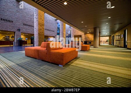 Innenansicht der Hotellobby und des Konferenzbereichs mit Einrichtung in warmen Farbtönen und Beleuchtung in kühlen Farbtönen Stockfoto