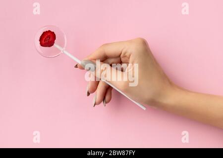 Womans Hand halten Lollipop aus natürlichen dehydrierten Beeren auf rosa gemacht Stockfoto