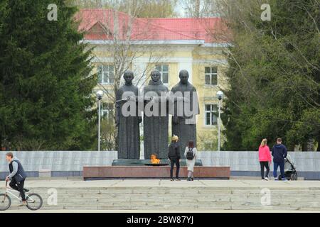 17-05-2020, Syktywkar, Russland. Menschen gehen in der Nähe des ewigen Flammendenkmals. Denkmal den Soldaten, die im Zweiten Weltkrieg, im großen patriotischen Krieg gefallen sind. Skulpturen von drei Frauen mit einem Gedenkkranz. Brennende Flamme leuchtend orange Farbe. Stockfoto