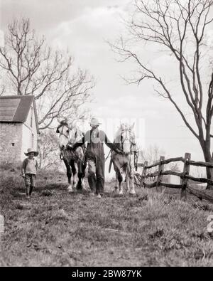 1920ER JAHRE FRÜHEN MORGEN LÄNDLICHEN BAUERNHOF ANONYMEN GROSSVATER UND ENKEL FÜHRENDEN GESPANNT ZUGPFERDE AUF FELD ZU PFLÜGEN BEGINNEN - F2206 HAR001 HARS ALTE MODE JUGENDLICH STIL PFERDE TEAMWORK SÖHNE FAMILIEN FREUDE LIFESTYLE LÄNDLICHEN ZUHAUSE LEBEN VEREINIGTE STAATEN KOPIE RAUM FREUNDSCHAFT VOLLER LÄNGE PERSONEN INSPIRATION VEREINIGTE STAATEN VON AMERIKA LANDWIRTSCHAFT MÄNNER VÄTER FÜHRENDE LANDWIRTSCHAFT B & W MORGEN NORDAMERIKA ZIELE NORDAMERIKA SÄUGETIERE FRÜH UND VÄTER BAUERN NIEDRIGEN WINKEL PFLÜGEN BEGINNEN BERUFE VERBINDUNG ENTWURF ANONYME SPLIT-RAIL GESPANNT JUNGTIERE SÄUGETIER MITTE ERWACHSENE MITTE ERWACHSENE MANN FRÜHLING SAISON FRÜHLING Stockfoto