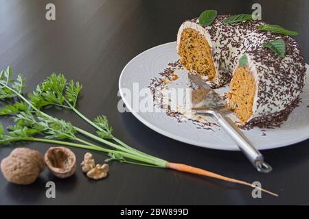 Hausgemachter Karottenkuchen auf einem großen weißen Gericht auf einem dunklen Holztisch. Selektiver Fokus, Kopierbereich Stockfoto