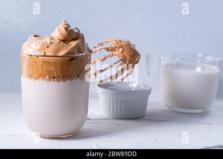 Dalgona Kaffee mit Schlagkaffee und Milch im Hintergrund. Eiskaffee und flauschiger koreanischer Kaffee. Stockfoto