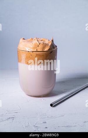 Trendy koreanischen Dalgona Kaffee mit einem Metallic-Stroh auf weißem Hintergrund. Vertikales Bild. Stockfoto