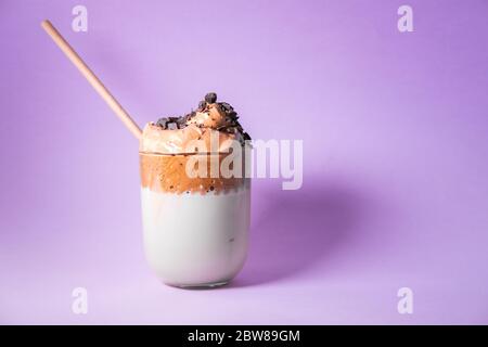 Dalgona Kaffee auf rosa Hintergrund mit Schokolade Chips und Bambus Stroh isoliert. Koreanischer Trenddrink. Stockfoto