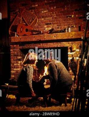 1960ER JAHRE 1970ER ROMANTISCHEN PAAR VOR DEM BACKSTEIN KAMIN IN SKI LODGE SITZEN EINANDER ANGUCKEN LIEBEVOLL TRAGEN PULLOVER - KS14331 PHT001 HARS LÄNDLICHE WÄRME HOME LEBEN KOPIE RAUM FREUNDSCHAFT HALBE LÄNGE DAMEN PERSONEN FÜRSORGLICH MÄNNER WINTERZEIT TRÄUME GLÜCK FREIZEIT NIEDRIGEN WINKEL BEZIEHUNGEN PULLOVER VERBINDUNG SHAG TEPPICH WÄRME MANTEL STILVOLL SCHNEE SCHUHE PERSÖNLICHE BEFESTIGUNG WINTERLICHE EMOTION MITTE ERWACHSENE MITTE ERWACHSENE MANN MITTE ERWACHSENE FRAU ROMANTISCH MITEINANDER KAUKASISCHE ETHNIZITÄT VOR ALTMODISCH Stockfoto