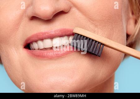 Reifes Modell mit Bambuszahnbürste in der Nähe des Mundes Stockfoto