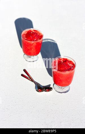 Gläser der traditionellen italienischen Sommer Dessert Erdbeere Granita oder Sorbet auf Hintergrund mit Schatten. Beereneis. Stockfoto