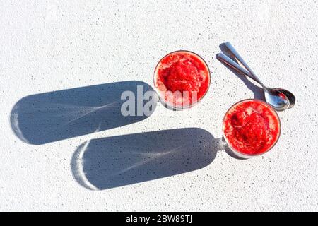 Gläser der traditionellen italienischen Sommer Dessert Erdbeere Granita oder Sorbet auf Hintergrund mit Schatten. Beereneis. Stockfoto