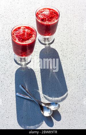Gläser der traditionellen italienischen Sommer Dessert Erdbeere Granita oder Sorbet auf Hintergrund mit Schatten. Beereneis. Stockfoto