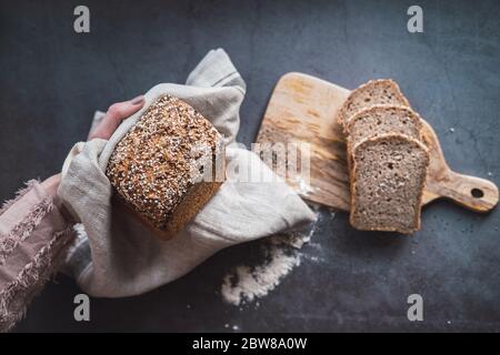 Die Hände der Frau halten einen Laib Buchweizenbrot mit Chia. Stockfoto