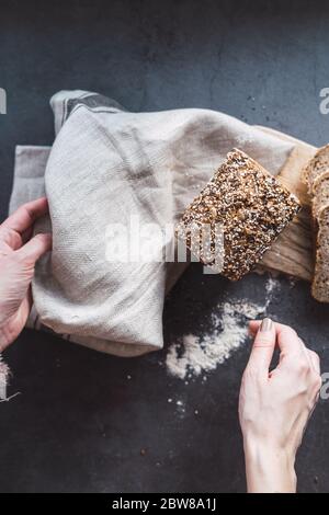 Frauenhände halten einen Laib gesunden Brotes mit Chia. Stockfoto