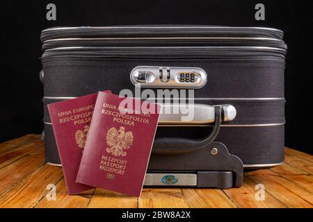Großer Reisekoffer und polnischer Reisepass. Gepäck für Reisen ins Ausland vorbereitet. Dunkler Hintergrund. Stockfoto