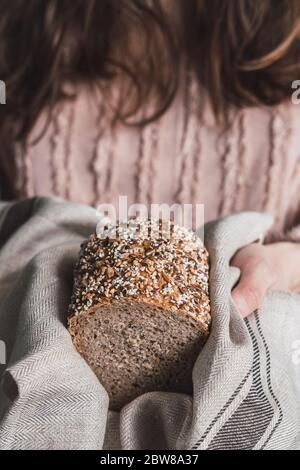 Frau hält einen Laib Brot mit mehreren Samen. Stockfoto