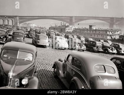 1930ER JAHRE AUTOS AUS DEN 1940ER JAHREN AUF DEM DEICH UND EIN SHOWBOOT UND SS ADMIRAL ANGEDOCKT AUF DEM MISSISSIPPI RIVER ST. LOUIS MISSOURI - R1885 HAR001 HARS WEITWINKEL-HOCHWINKEL LOUIS UND AUTOS AUFREGUNG MISSOURI FORTSCHRITT ERHOLUNG DAMPF ANGETRIEBEN AUF BERUFE KONZEPTIONELLE ANGEDOCKTE AUTOS ST. FAHRZEUGE DEICH SS SS ADMIRAL SCHLEPPBOOT ADMIRAL SCHWARZ UND WEISS HAR001 MIDWEST MIDWESTERN MISSISSIPPI MISSISSIPPI RIVER MO VERTÄUTE ALTMODISCHE SCHAUFELRAD ST. LOUIS Stockfoto