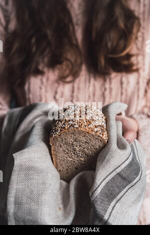 Frau hält einen Laib Dinkelbrot auf einem rustikalen Tuch Stockfoto