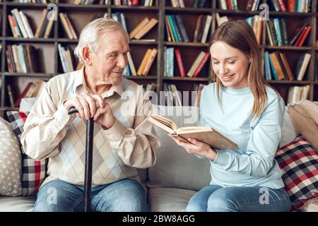 Vater und Tochter zu Hause Bibliothek sitzenden Mann zu Frau Buch lesen fröhlich zuhören Stockfoto