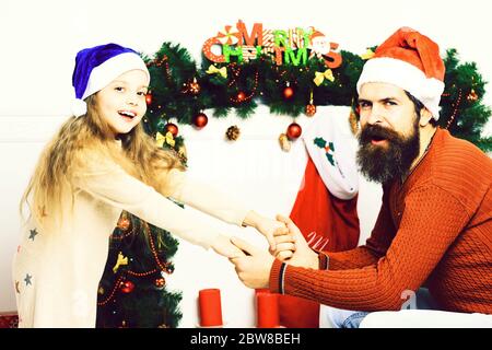 Niedliche blonde lächelndes Mädchen und schönen bärtigen Mann mit langem Bart in weihnachten roten Hut und Pullover hält die Hände um weihnachtsdekoration, auf weißem Studio Hintergrund Stockfoto