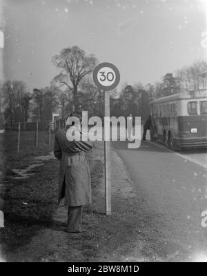 Ein Mann, der auf das Straßenschild mit der Geschwindigkeitsbegrenzung von 30 Meilen pro Stunde schaut. 1935 Stockfoto