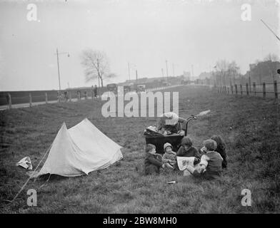 Kinder haben ein Picknick auf einem Stück Gras neben der Straße. 1938 Stockfoto