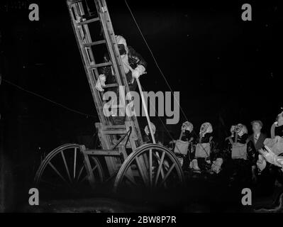 Mitglieder der Sidcup Feuerwehr demonstrieren das Aufsteigen einer Leiter mit Schutzkleidung gegen Gas. 29 November 1937 . Stockfoto