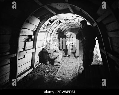 Männer vom Lancashire Mine Rescue Center überprüfen ihre Umgebung, während sie durch den Minenschacht ziehen. 1937 . Stockfoto