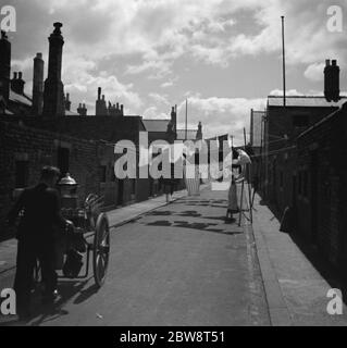 Eine Frau hängt ihre Wäsche an der Linie auf der anderen Straßenseite in Blyth, Northumberland, England. 1936 . Stockfoto