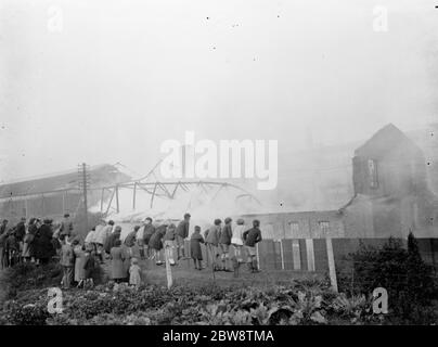 Kinder klettern auf einen Zaun, um das Feuer in der Vickers Fabrik in Crayford, Kent zu beobachten. 1936 Stockfoto