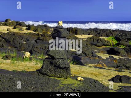 An der zerklüfteten Küste von South Point, Big Island of Hawaii, haben die Einheimischen einen Altar aus Lavastein und Korallen eingerichtet. Grüner Sand genannt Olivine legt Streuung Stockfoto