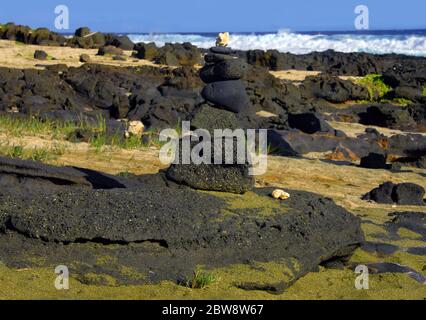 Grüner Sand, auf der Big Island von Hawaii, bildet eine Abdeckung an der Basis von Alter auf einem menschenleeren und ruhigen Strandabschnitt. Wellen schlagen gegen felsige Ufer Stockfoto