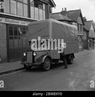 Der Fahrer steigt in den Bedford LKW der Standard Telephone and Cables Company Ltd, vor ihrem Geschäft geparkt. 1936 . Stockfoto