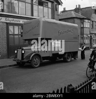 Ein Arbeiter lädt Kisten in einen Bedford LKW der Standard Telephone and Cables Company Ltd, vor ihrem Geschäft geparkt gehören. 1936 . Stockfoto