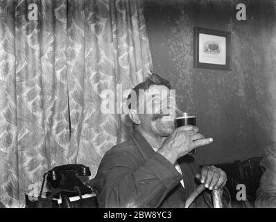 Bezahlen Sie in der Nacht im Rat und Sparrow Club in Eynsford, Kent. Herr Charlie Meadows bei einem Bier. 1939 Stockfoto