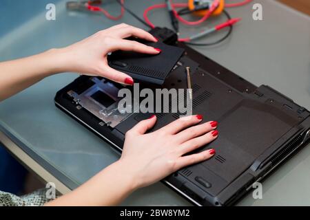 Mädchen entfernt oder installiert eine Laptop-Abdeckung während der Reparatur Stockfoto